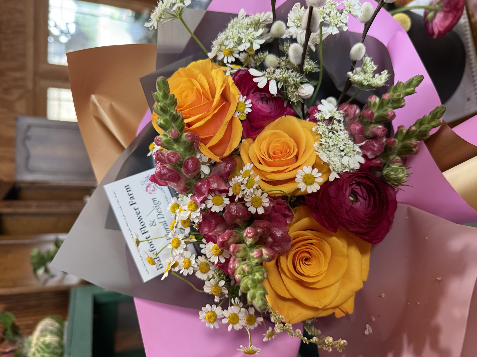 Blush pink roses and ranunculus arrangement with Barefoot Flower Farm card