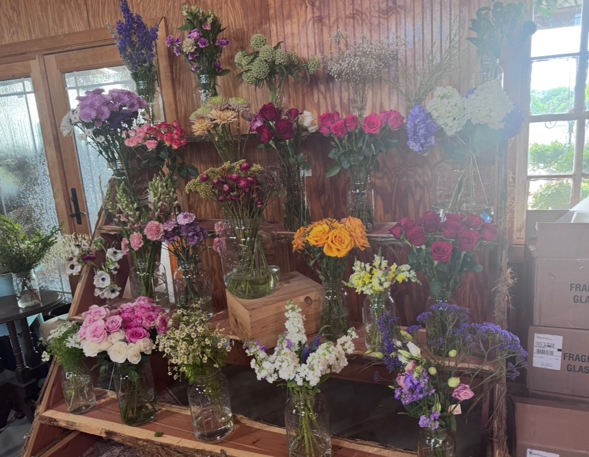 Rustic flower shop display with vases of roses, hydrangeas, and seasonal blooms