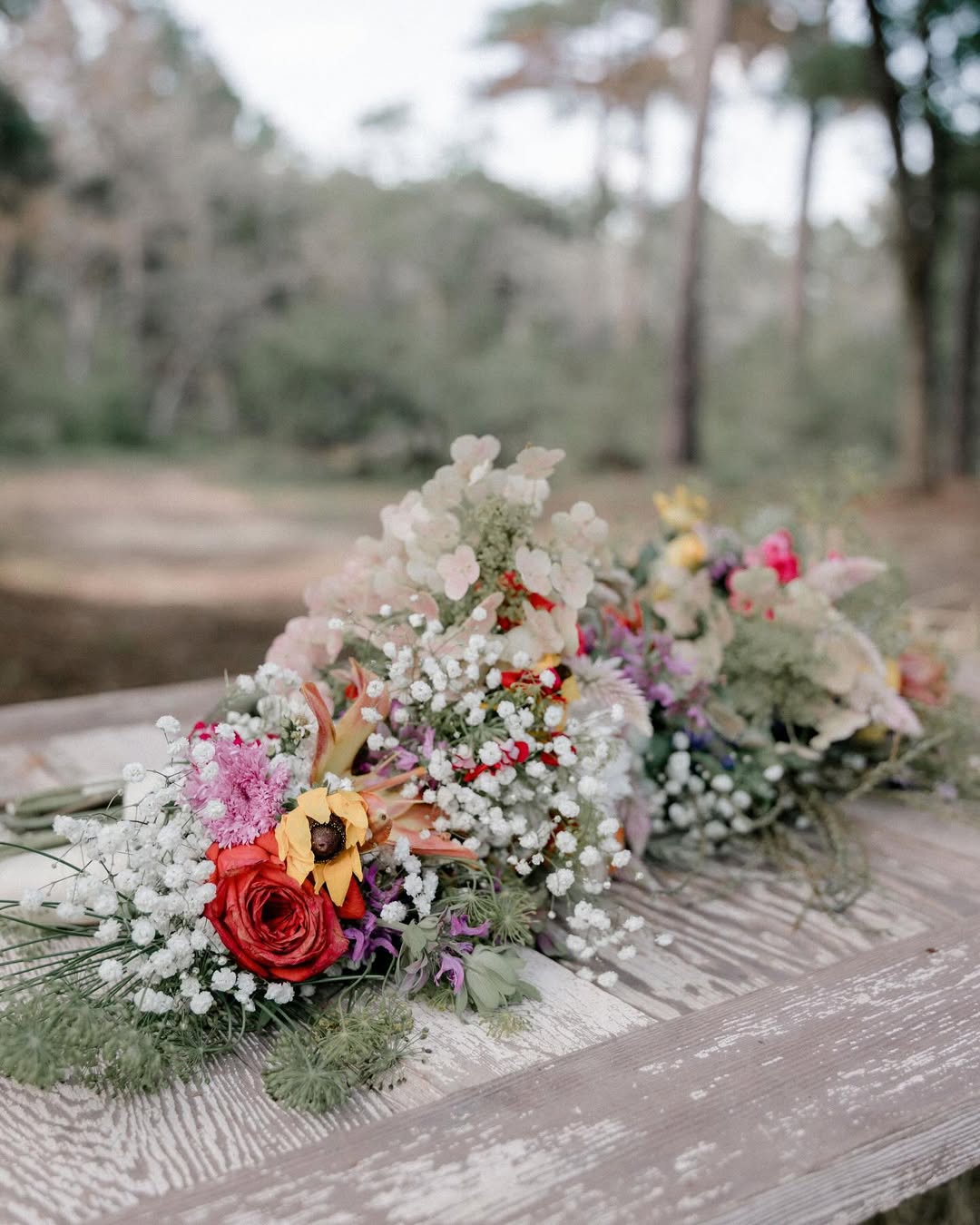 Garden-style bridal bouquet with roses, baby's breath, and wildflowers on rustic wood
