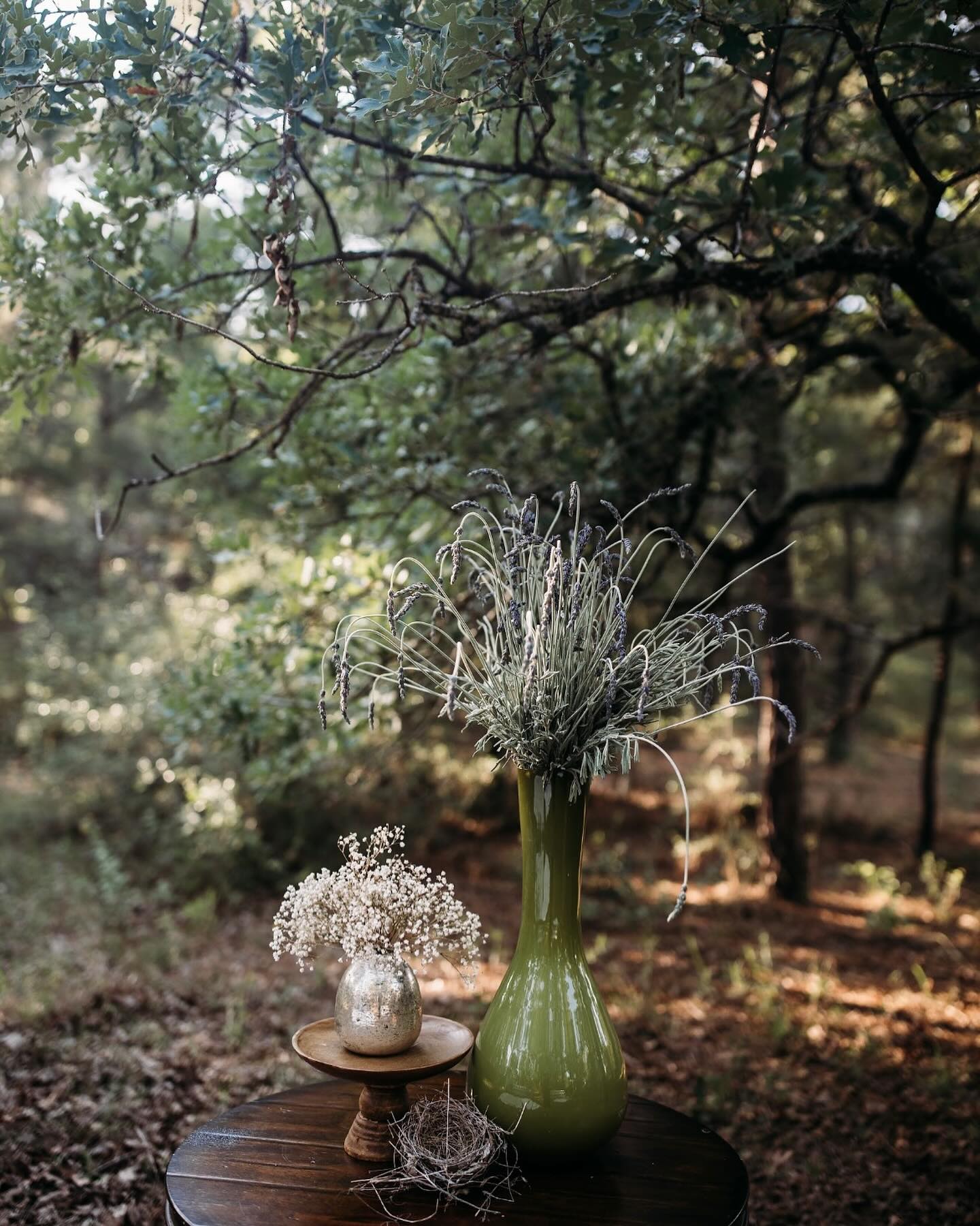 Lavender and baby's breath vase arrangement under oak trees for ceremony decor